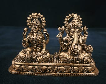 Peut inclure: Statue en métal doré des divinités hindoues Ganesha et Lakshmi. Les statues sont assises sur un socle décoré d'éléphants.