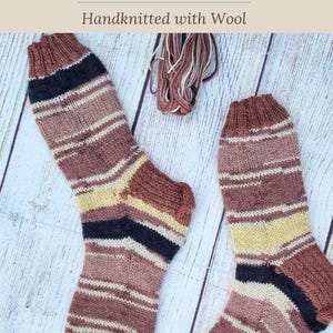 May include: A pair of handknitted wool socks featuring horizontal stripes in shades of brown, black, and cream. The text Soft and Snuggly Coffee Socks Handknitted with Wool and www.hearthearthcrafts.com is visible on the image.