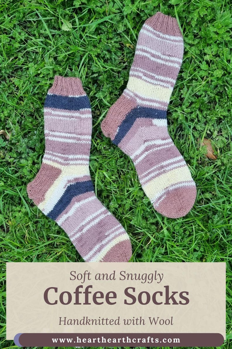 May include: A pair of hand-knitted wool socks featuring horizontal stripes in shades of mauve, cream, and dark navy blue. The text on the image reads: Soft and Snuggly Coffee Socks, Handknitted with Wool, www.hearthearthcrafts.com.