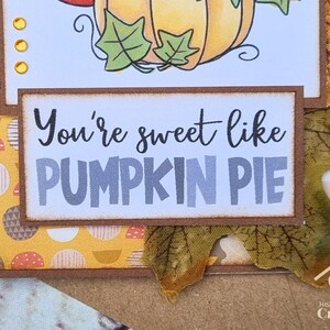 Peut inclure: Une carte de v&oelig;ux artisanale avec un panneau rectangulaire portant le texte noir et gris You're sweet like PUMPKIN PIE. La carte est d&eacute;cor&eacute;e avec du papier &agrave; motifs jaunes, de petites gemmes dor&eacute;es et une d&eacute;coupe de feuille d'automne en tissu.