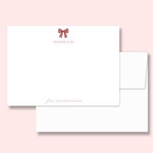 May include: White thank you cards with a dusty rose bow illustration and the words "THANK YOU" printed above the blank space. The card includes the name "ARIYA WREN KOONDEL" in a script font. A white envelope is included.