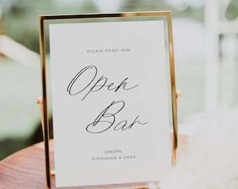 May include: A gold-framed sign with white background and black text that reads "Please enjoy our Open Bar Cheers. Stephanie & Chad".