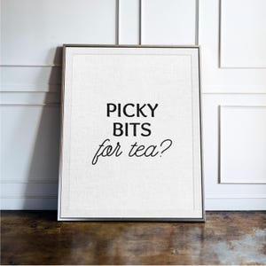 May include: A rectangular framed wall art piece featuring a white textured background with the black printed text PICKY BITS for tea? The text is arranged in three lines with the first two in a bold sans-serif font and the third in italics.