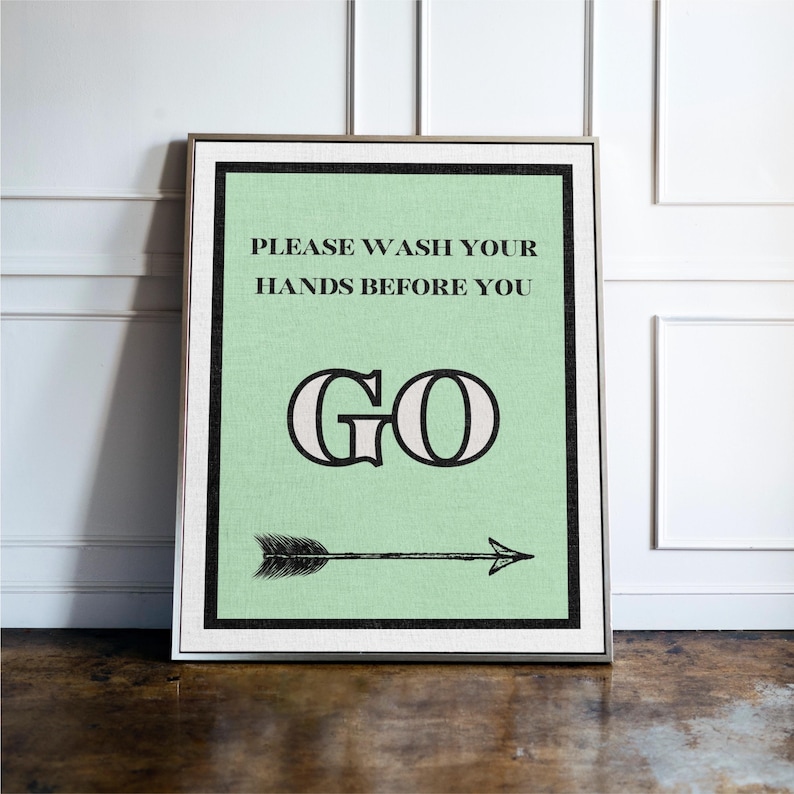 May include: Framed wall art with a mint green background and black border. The text "PLEASE WASH YOUR HANDS BEFORE YOU GO" is displayed in black, with a decorative "GO" and an arrow pointing right.