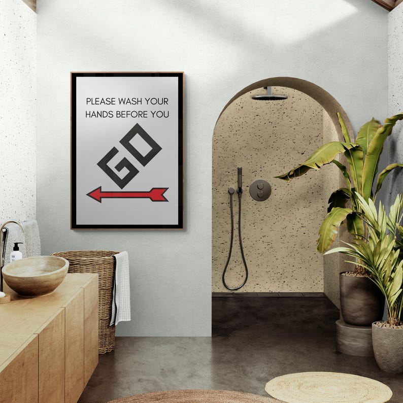 May include: A black framed poster with white background and red and black graphic. The poster reads "Please wash your hands before you go" with a red arrow pointing to the right.