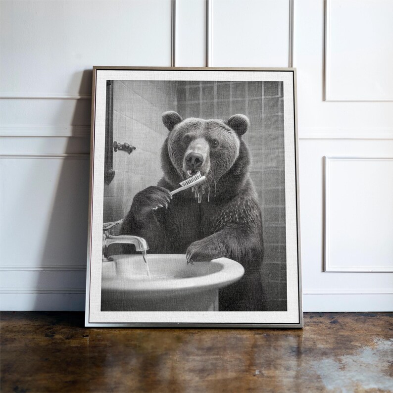 May include: A black and white photograph of a bear brushing its teeth in a bathroom. The bear is standing in front of a sink and holding a toothbrush in its mouth. The bear is looking at the camera.