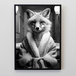 Puede incluir: Impresi&oacute;n en blanco y negro enmarcada de un zorro con una bata de felpa. El zorro est&aacute; centrado en el marco, mirando directamente al espectador. El fondo sugiere un ba&ntilde;o, con un lavabo y un espejo visibles.