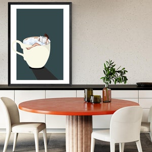 May include: A framed illustration of a woman relaxing in a cup of coffee, reading a book. The cup is white with a dark blue background.