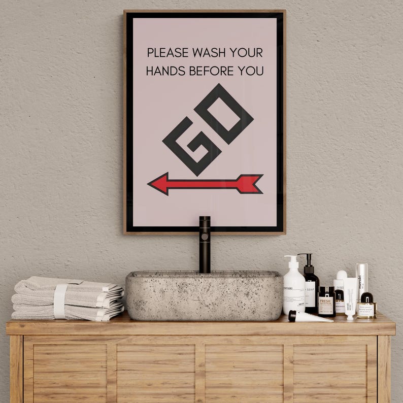 May include: A bathroom vanity with a concrete sink, a black faucet, and a framed sign that reads "Please wash your hands before you GO" with a red arrow pointing to the right. The vanity has a wooden countertop and shelves with towels and toiletries.