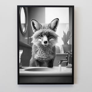 Puede incluir: Impresi&oacute;n en blanco y negro enmarcada de un zorro en un ba&ntilde;o. El zorro mira al espectador mientras est&aacute; sobre un lavabo con un grifo abierto. Un tubo de pasta de dientes y una planta son visibles en el fondo.