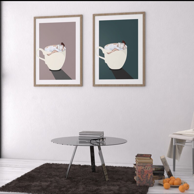 May include: Two framed prints of a woman reading a book while relaxing in a cup of coffee. The prints are in different color schemes, one with a pink background and the other with a teal background.
