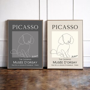 May include: Two framed rectangular wall art prints featuring a continuous line drawing of a Cavapoo dog. The left print has a dark grey background, and the right print has a cream background. Both include the text PICASSO, THE CAVAPOO, MUSÉE D'ORSAY.