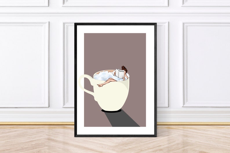 May include: A framed illustration of a woman relaxing in a large white coffee cup with a book. The woman is wearing a white dress and has brown hair. The background is a light brown color.