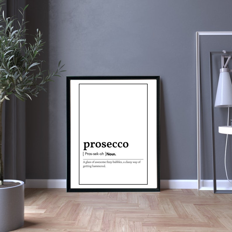 May include: A framed black and white print with the definition of "prosecco." The definition reads: "A glass of awesome fizzy bubbles, a classy way of getting hammered." The print is displayed on a wooden floor.