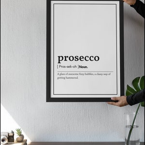 May include: A framed black and white print with the definition of "prosecco". The definition reads: "A glass of awesome fizzy bubbles, a classy way of getting hammered."