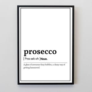 May include: A framed print with the word "prosecco" in a bold, black font. Below the word is the phonetic pronunciation and a definition: "A glass of awesome fizzy bubbles, a classy way of getting hammered."