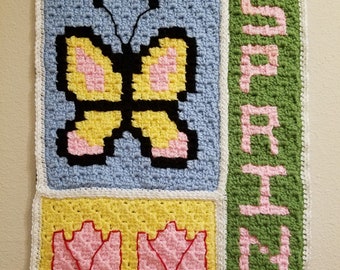 May include: Crocheted wall hanging with a yellow butterfly, pink tulips, and the word "Spring" in pink letters on a green background.