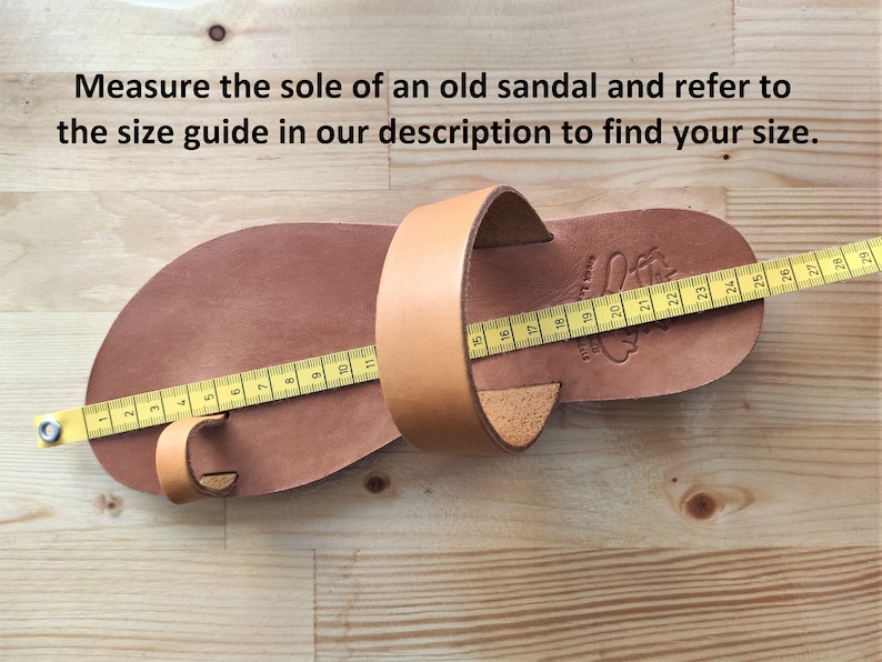 May include: A brown leather sandal with a yellow measuring tape across the sole. The tape measures 24 cm in length. The sandal has a strap that goes around the ankle and a toe loop.