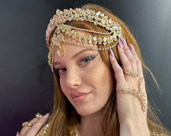 May include: A woman wearing a gold jeweled headpiece, necklace, and bracelets. The jewelry features large, faceted stones and intricate designs.