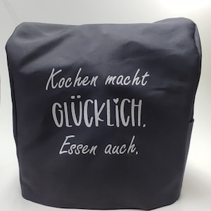 May include: A dark grey kitchen appliance cover with white text. The text reads "Kochen macht GLÜCKLICH. Essen auch." The cover is made of a smooth material, possibly water-resistant. It has a simple, functional design.