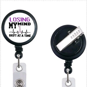May include: Black retractable badge holder with a white circle featuring the text "Losing My Mind 1 Shift At A Time" with a purple heartbeat graphic.