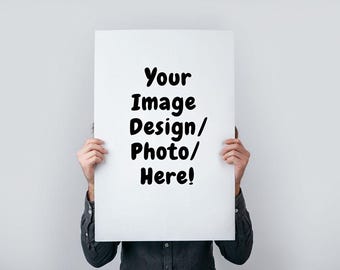 May include: A white rectangular sign held up by a person, with the text "Your Image Design/Photo/Here!" in black, bold font. The person is wearing a dark button-down shirt against a plain white background.