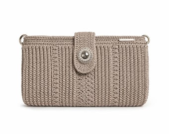 Puede incluir: Bolso bandolera de crochet beige con cierre plateado. El bolso presenta un diseño acanalado texturizado con un patrón decorativo en la parte delantera. Anillos plateados están unidos a las esquinas superiores para una correa.