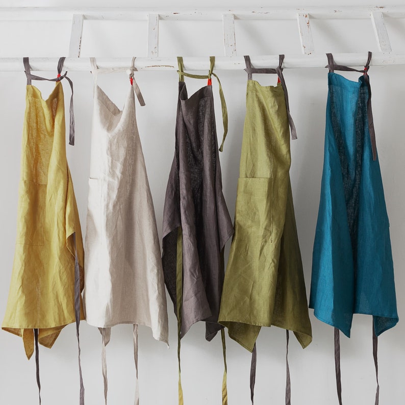Five linen apron photo and you can see the light on them shows the special textured of linen. Yellow apron with charcoal tie, flax apron with flax tie, charcoal apron with green tie, green apron with charcoal tie and blue apron with charcoal tie.