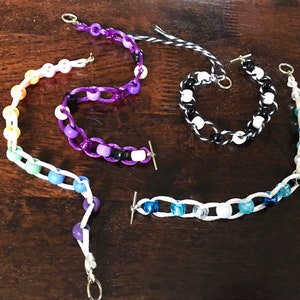 Peut inclure: Quatre bracelets en perles avec des schémas de couleurs différents. Les bracelets sont faits avec une ficelle blanche et des perles de différentes couleurs. Les bracelets ont des fermoirs et des boutons argentés.