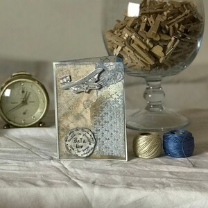 L'ebrezza del viaggio - Biglietto beige e blu - con fiori, scritte, timbro e aereo, per un messaggio avventuroso - Handmade