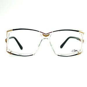 May include: Clear plastic framed eyeglasses with gold accents and black arms. The brand name "Celine" is printed on the right arm.