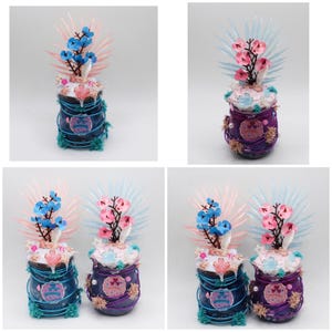 Peut inclure: Des pots en verre décoratifs avec des compositions florales. Chaque pot est enveloppé de fil de fer et orné de fleurs artificielles bleues, roses et blanches. Les pots ont un aspect artisanal et fantaisiste.