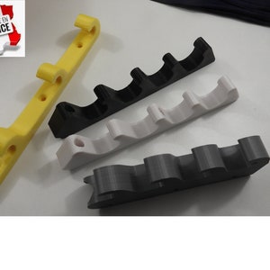 Peut inclure: Quatre supports muraux imprimés en 3D en jaune, noir, blanc et gris. Les supports ont plusieurs fentes pour tenir des objets.