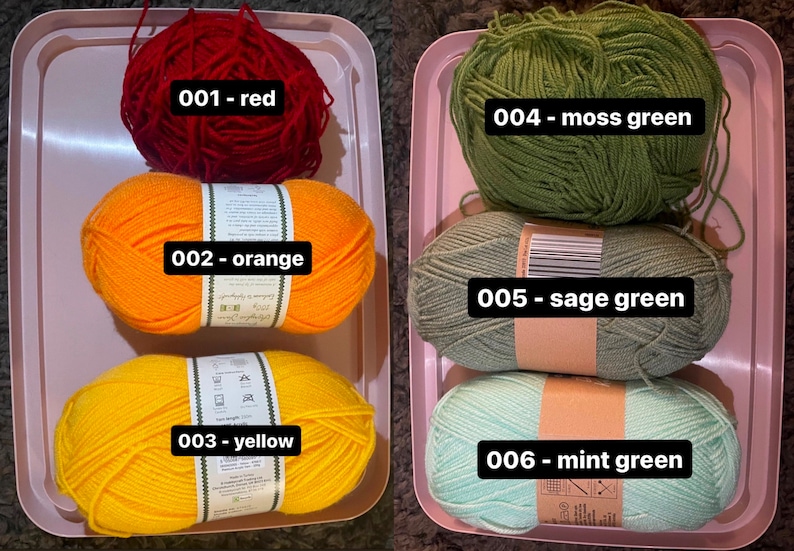 May include: A selection of colorful yarn skeins in a pink tray. The colors include red, orange, yellow, moss green, sage green, and mint green. Each skein is labeled with a number and color name, ideal for knitting or crochet projects.