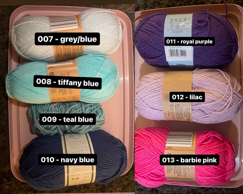 May include: A selection of colorful yarn skeins in a pink tray. Colors include grey/blue, tiffany blue, teal blue, navy blue, royal purple, lilac, and barbie pink. Each skein has a label with a number and color name.