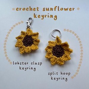 Peut inclure: Deux porte-clés en forme de tournesol crochetés, l'un avec un fermoir mousqueton, l'autre avec un anneau fendu. Les tournesols sont jaunes avec des centres bruns. Le texte indique "crochet sunflower keyring".