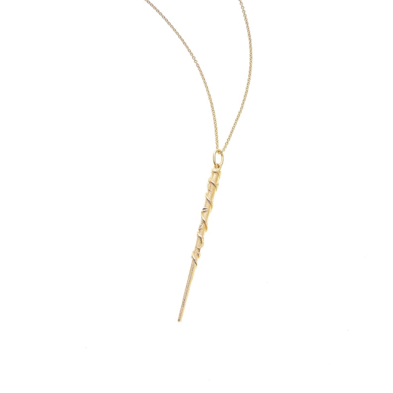 Puede incluir: Un collar de oro con un colgante en forma de varita retorcida.