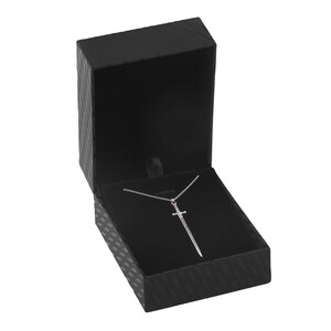 Puede incluir: Un collar con un colgante de espada de plata con una piedra roja en la empu&ntilde;adura, presentado en una caja de joyer&iacute;a de terciopelo negro.