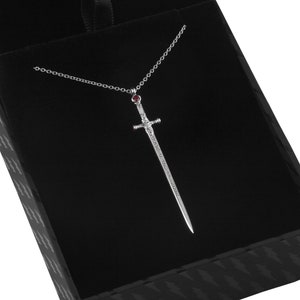 Puede incluir: Un collar con un colgante de espada de plata con una piedra preciosa roja en la empu&ntilde;adura. La espada tiene una inscripci&oacute;n que dice "The Sword of the Last Jedi".