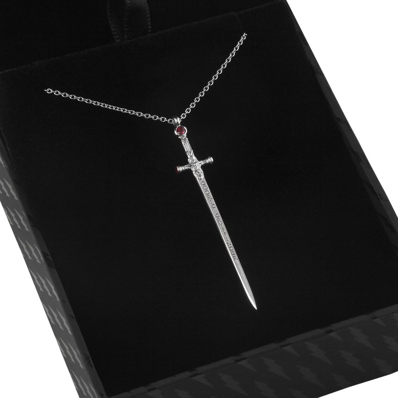 Puede incluir: Un collar con un colgante de espada de plata con una piedra preciosa roja en la empu&ntilde;adura. La espada tiene una inscripci&oacute;n que dice "The Sword of the Last Jedi".