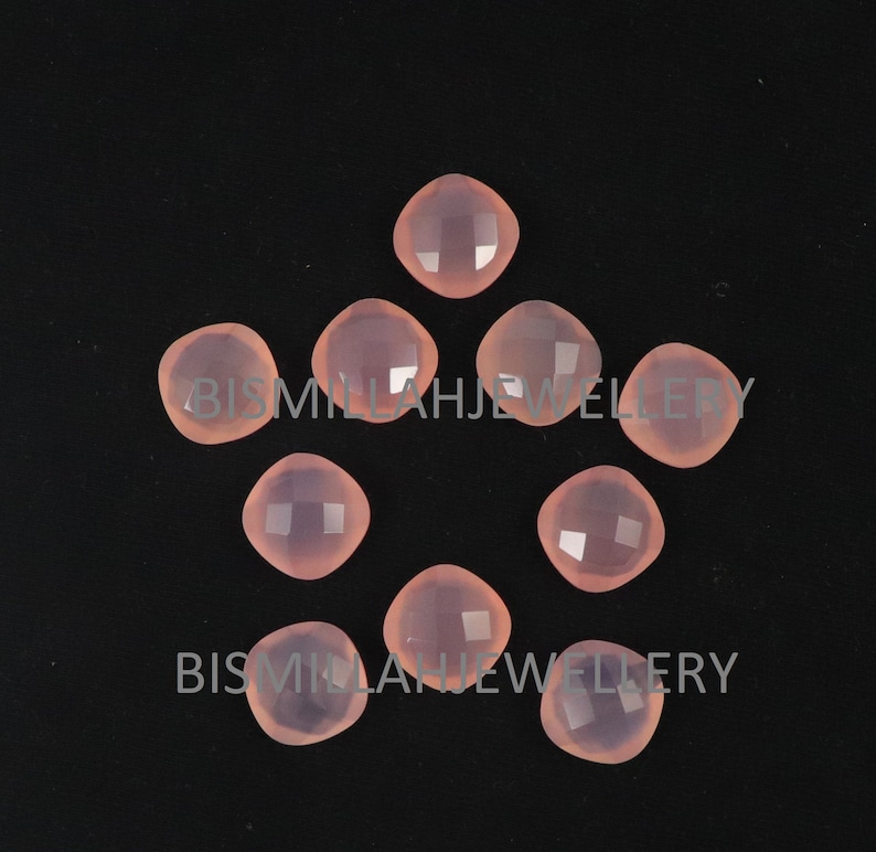 May include: Ten pink gemstone cabochons, each with a faceted surface, arranged in a circular pattern on a black background.