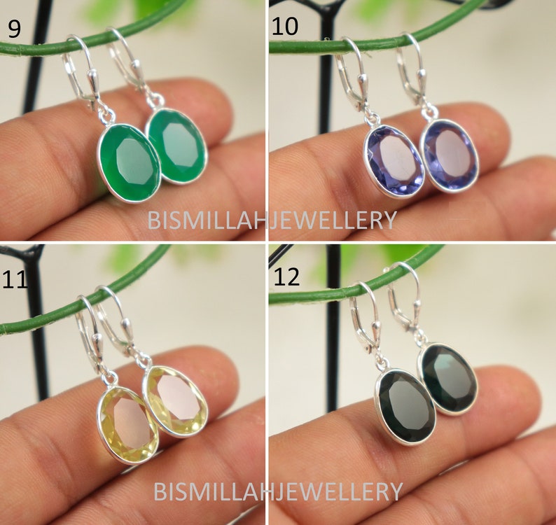 May include: Four pairs of silver dangle earrings with oval-shaped gemstones. The earrings are shown on a hand against a green background. The gemstones are green, purple, yellow, and black.