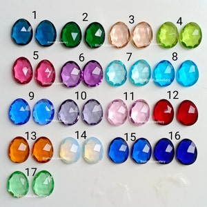 Peut inclure: Assortiment de 17 cabochons de pierres précieuses facettées de différentes couleurs, notamment bleu, vert, rouge, violet et rose. Les pierres précieuses sont disposées en rangées de deux, avec les numéros 1 à 17 imprimés au-dessus de chaque pierre.