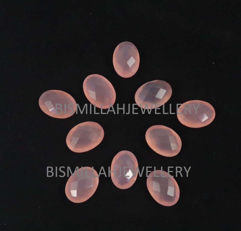 May include: Ten oval-shaped, translucent pink chalcedony gemstones with faceted surfaces. The stones are arranged in a starburst pattern on a black background.