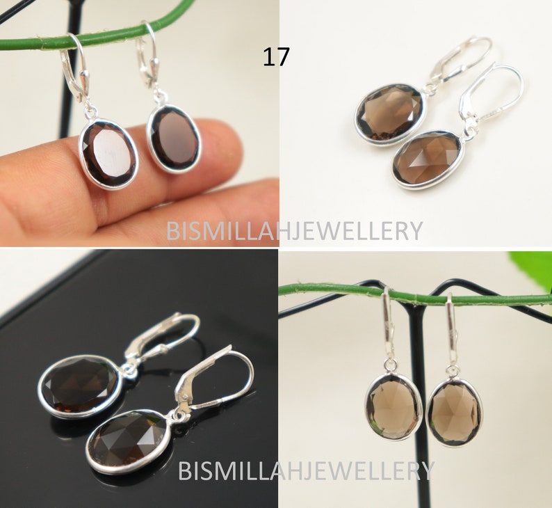May include: A pair of silver earrings with brown oval-shaped gemstone drops. The earrings have a hook closure. The earrings are displayed on a white background.