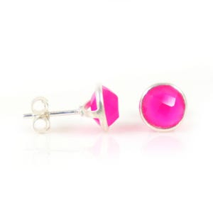 May include: A pair of silver stud earrings with bright pink gemstone accents. The earrings have a simple, elegant design.