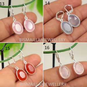 May include: Four pairs of silver dangle earrings with different colored gemstone drops. The earrings are displayed on a hand with a green background. The earrings are numbered 13, 14, 15, and 16.