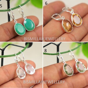 May include: Four pairs of silver dangle earrings with oval-shaped gemstones. The earrings feature a green, yellow, clear, and light green gemstone.