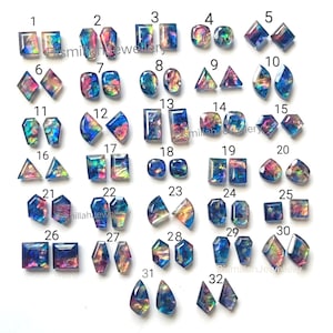 Può includere: Trentadue cabochon di opale iridescenti in varie forme e dimensioni, tra cui ovale, a goccia, quadrato, rettangolare e triangolare. Le opali sono un mix di blu, viola, verde e rosa.