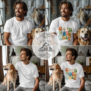 May include: A white t-shirt with a colorful graphic that says "Good Vibes Only" with a peace sign and a daisy. The shirt is being modeled by a person with a dog.